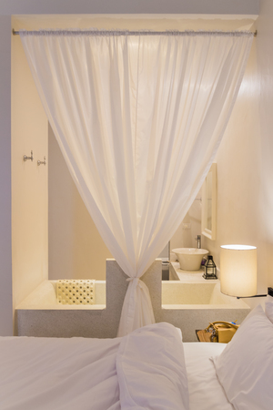 Beautiful Interior of bedroom in old style hotel. It has bath tub inside and separated by cloth curtainの写真素材