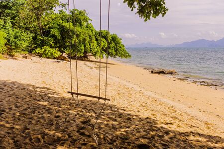An empty simple wooden swing on tropical beach, South of Thailandの写真素材