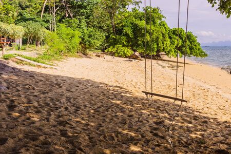 An empty simple wooden swing on tropical beach, South of Thailandの写真素材