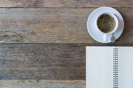 Open notebook on wooden background with coffee cup.の写真素材