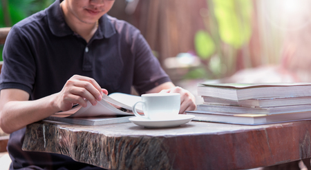 The boys are enjoying reading books and drinking coffee. In the garden with morning sunlight, Lens flare filter .の写真素材