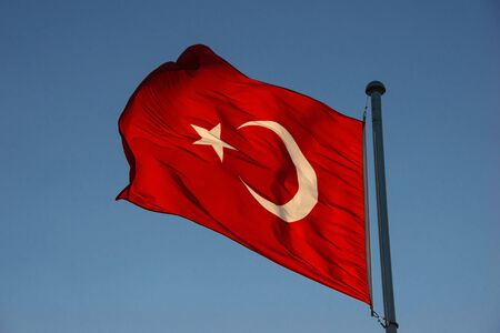 Red bright waving Turkish flag at sunsetの写真素材