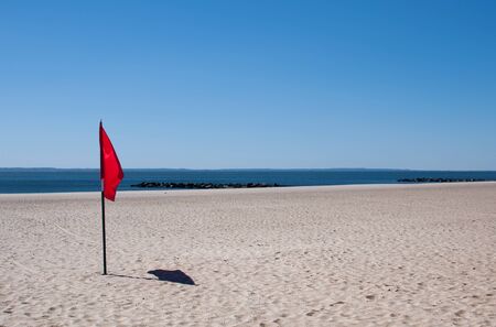 Red warning flag on a sandy beach near the seaの写真素材