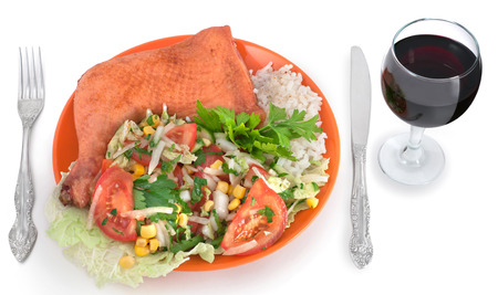 Chicken and salad on the plate with fork, knife and a glass of wineの写真素材