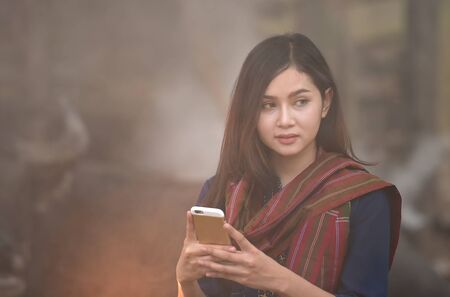 Asian woman wearing traditional dress texting on a smartphoneのeditorial素材