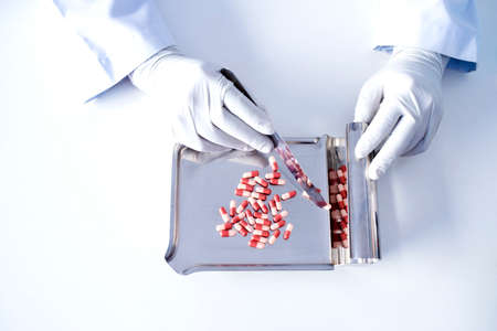 Focus on the picture of the doctor's hand, the colored pill on the dispensing tray by an antiviral drug pharmacist.の写真素材