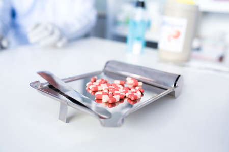 Focus on the picture of the doctor's hand, the colored pill on the dispensing tray by an antiviral drug pharmacist.の写真素材