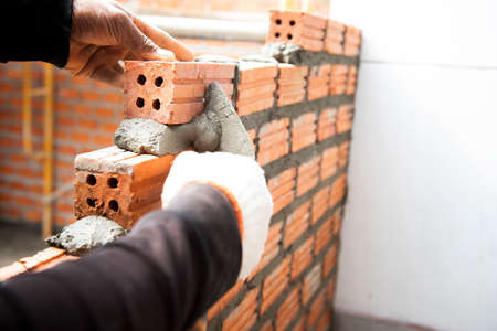 Brickworkers install bricks on the exterior walls with a knife putty trowel,の写真素材