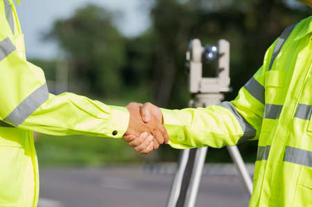 Road construction workers use orthogonal surveyors to measure angles in the horizontal and vertical planes on road construction sites. Engineers and architects help to inspect before the work is delivered.の写真素材