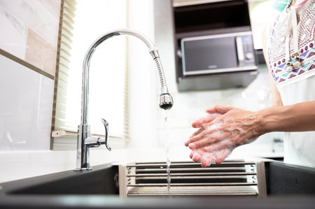 Woman washing her hands with soap over sink in luxury kitchen , concept of healthの写真素材