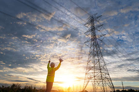 Engineer inspecting high voltage tower with radio,Engineer inspecting high voltage tower