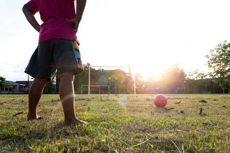 take off football shoes Outdoor action sports of a group of children playing soccer for a workout in a rural community in the evening sun.の写真素材