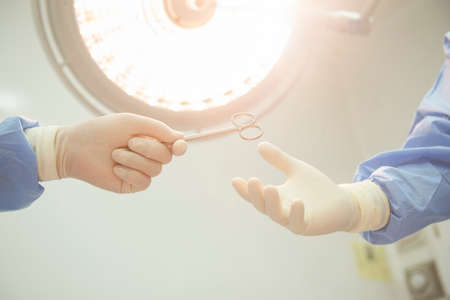 A team of Asian surgeons hand out surgical tools to other doctors while operating patients....