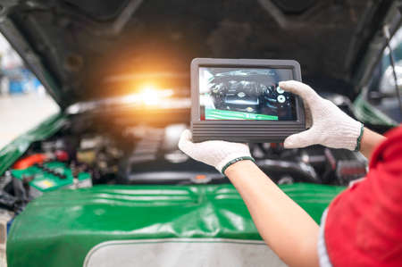 Professional mechanic and check car engine with computer diagnostic software.Expertise mechanic working in automobile repair garage.の写真素材