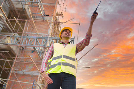 Construction engineers use radios to control work at construction sites. industrial workers wearing helmetsの写真素材