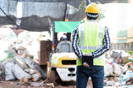 Close-up of a worker with a recycling bin moving a forklift in a steel mill waste collection plant.