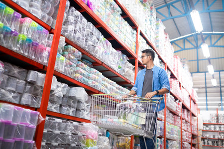 Asian man shopping. Handsome smiling young man shopping for household items with supermarket and shopping cart.の写真素材