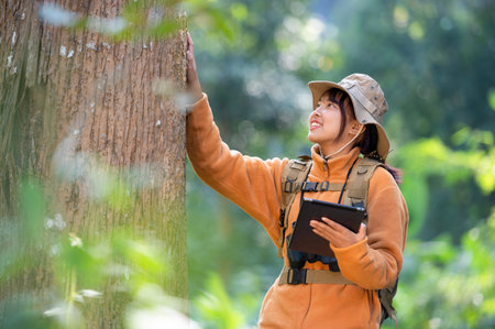 Young tourist woman in a yellow coat hugging a tree in the forest of eco love looking up at the...