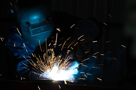 Industrial workers at steel structure welding plant A welder is welding metal parts in a small workshop.の写真素材