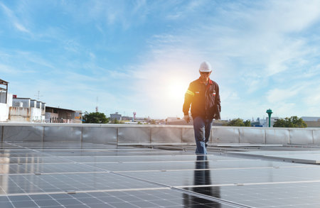 technician inspecting solar panels on factory roof Check and maintain the solar panel roof A team of technicians installing solar panels on the roof of a high-rise buildingの写真素材