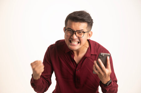 Cheerful young asian man isolated on yellow background, presentation concept, young asian businessman smiling with arms crossed in isolated backgroundの写真素材