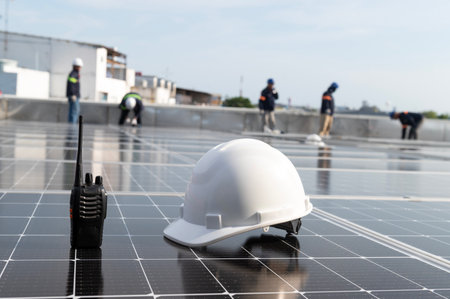 Solar installation concept White helmet blueprint and walkie talkie on solar panel High security wearing helmet at work site installing solar panels on the roofの写真素材