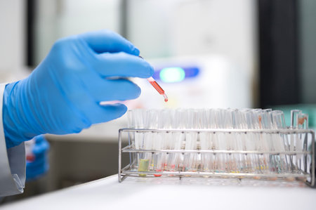 Medical professionals in laboratory with blood sampling tubes and rack with other samples. A medical laboratory specialist/laboratory technician collects vascular samples for study.の写真素材