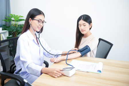 Asian female doctor with blood pressure monitor of female patient at hospital concept for health care and peopleの写真素材