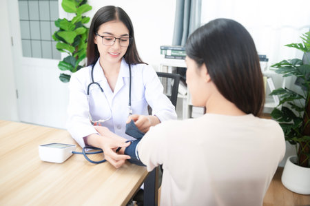 Asian female doctor with blood pressure monitor of female patient at hospital concept for health care and peopleの写真素材
