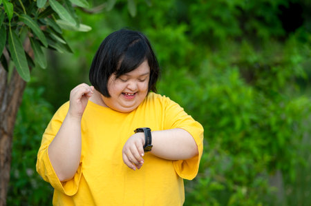 Girl with Down syndrome or autism looking at the time While walking outdoors in the parkの写真素材