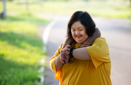 Girl with Down syndrome or autism looking at the time While walking outdoors in the parkの写真素材