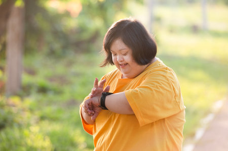 Girl with Down syndrome or autism looking at the time While walking outdoors in the parkの写真素材