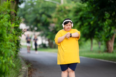 Girl with Down syndrome or autism looking at the time While walking outdoors in the parkの写真素材