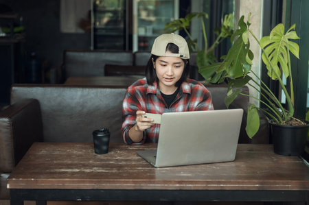 Asian woman holding plastic credit card and using laptop Online shopping concept. Tone image.の写真素材