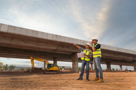The chief civil engineer is introducing inspection of a road or expressway construction project under the road to an intern. At the expressway construction siteの写真素材