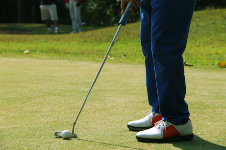 Golfer putting golf ball on the green golf. lens flare on sun set evening time.の写真素材
