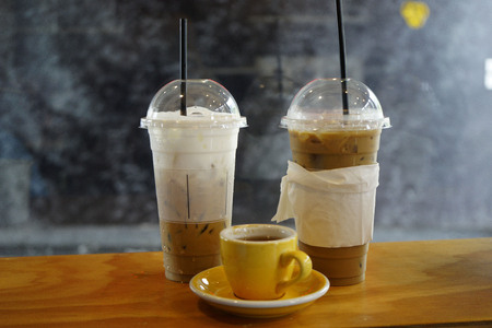 Ice coffee and hot coffee with milk on the wooden tableの写真素材
