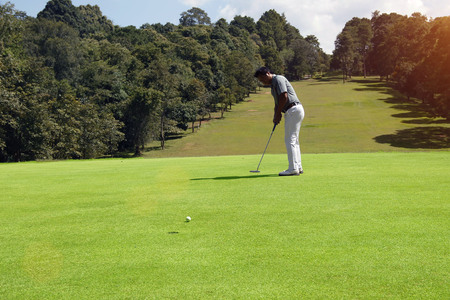 Golfer putting golf in beautiful golf course in the evening golf course with sunshine in thailand