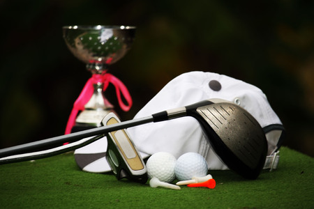 Collection of golf equipment resting on green grass with green background