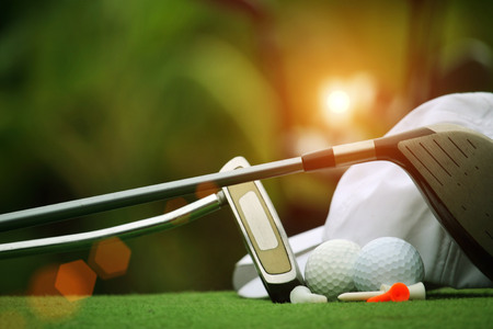 Collection of golf equipment resting on green grass with green backgroundの写真素材