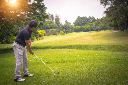 Golfer playing golf in the evening golf course, on sun set evening time. Man playing golf on a golf course in the sun.の写真素材