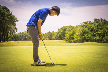 Golfer putting golf in the evening golf course, on sun set evening time. Man playing golf on a golf course in the sun.の写真素材