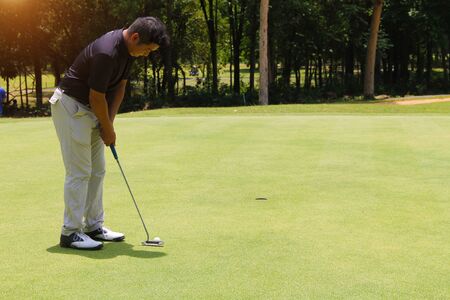 Golfer putting golf in the evening golf course, on sun set evening time. Man playing golf on a golf...