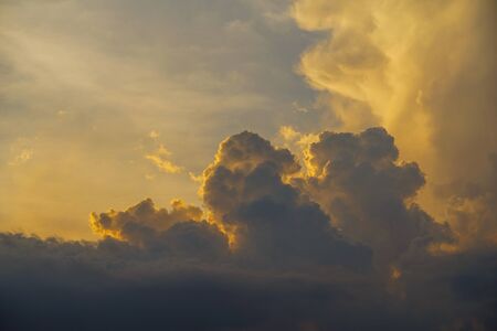 Colorful dramatic sunset sky with the sun of orange tones behind the mountains in the evening time.                                の写真素材