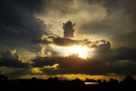 Colorful dramatic sunset sky with the sun of orange tones behind the mountains in the evening time.                                の写真素材
