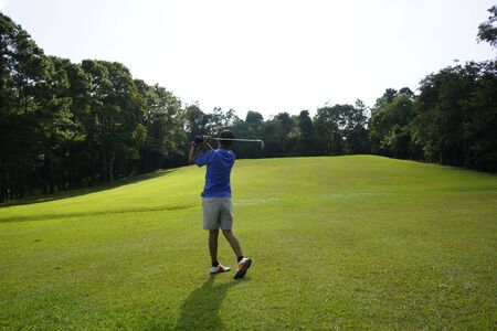 Asian man golfer playing golf at golf course . Golfer holding club and hitting the ball on the green grass. ,Sport healthy holiday lifestyle Concept                               の写真素材