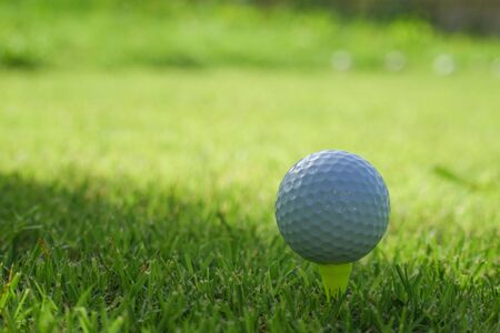 Golf ball on tee in the evening golf course with sunshine background.                               の写真素材