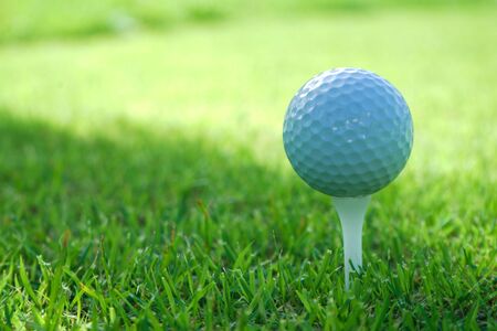 Golf ball on tee in the evening golf course with sunshine background.                               の写真素材