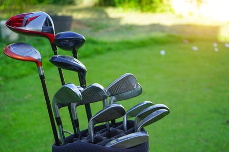 Closeup old golf bags on green. Set of golf clubs over green field background.                               の写真素材