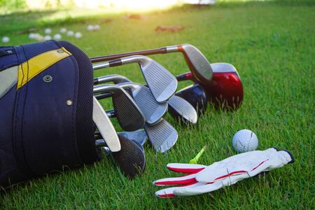Closeup old golf bags on green. Set of golf clubs over green field background.                               の写真素材